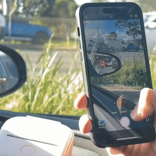 A person taking a photo of the side mirror from inside a car.