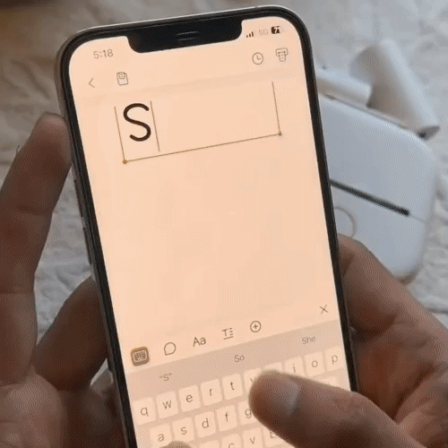 Person using smartphone keyboard to type letter 'S' in a text box.